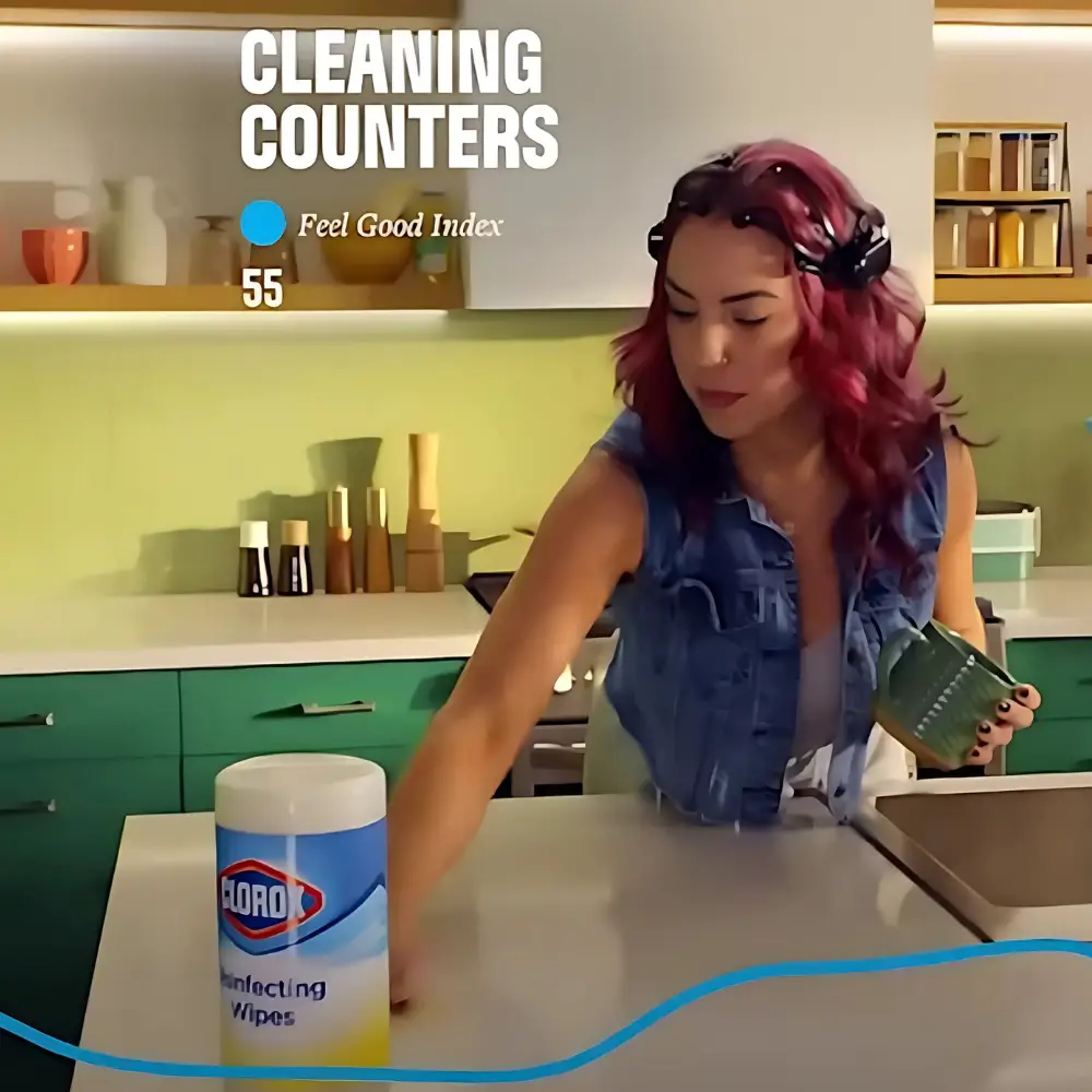 A person wearing an Emotiv EEG headset while cleaning a kitchen counter during a product study